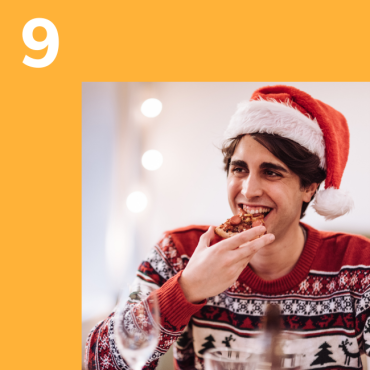 Photo of a man in a santa hat eating a mince pie