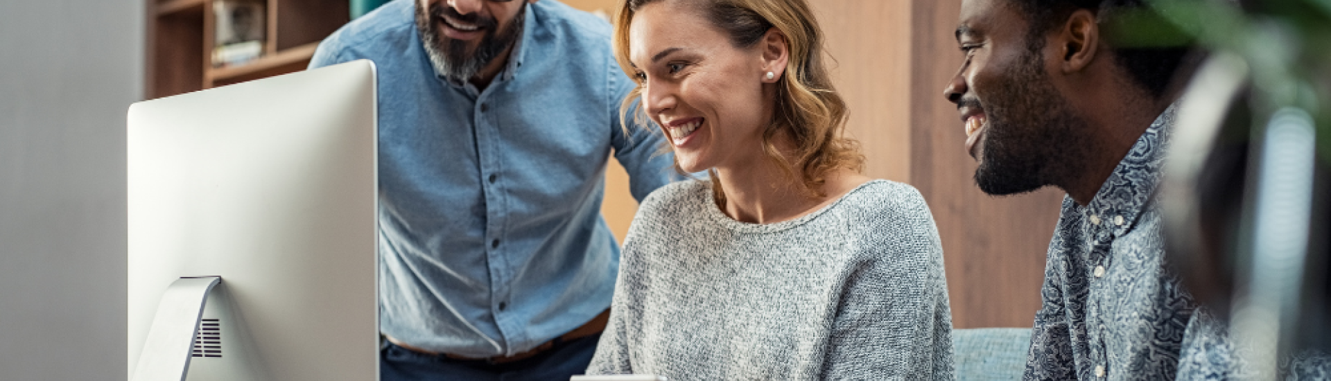 three people smiling looking at a computer screen