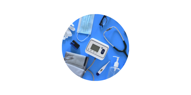 Medical equipment on a table: stethoscope, blood pressure reader, mask, clinical gloves, thermometer