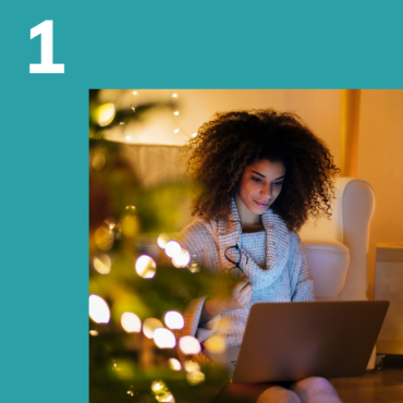 Woman looking at her computer surrounded by Christmas lights