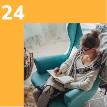 Photo of a woman sitting in a cosy chair writing in a notebook