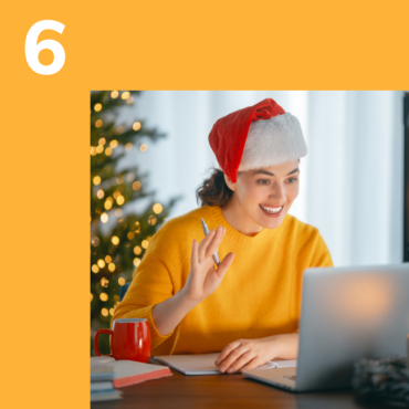 Photo of woman in santa hat waving at a computer