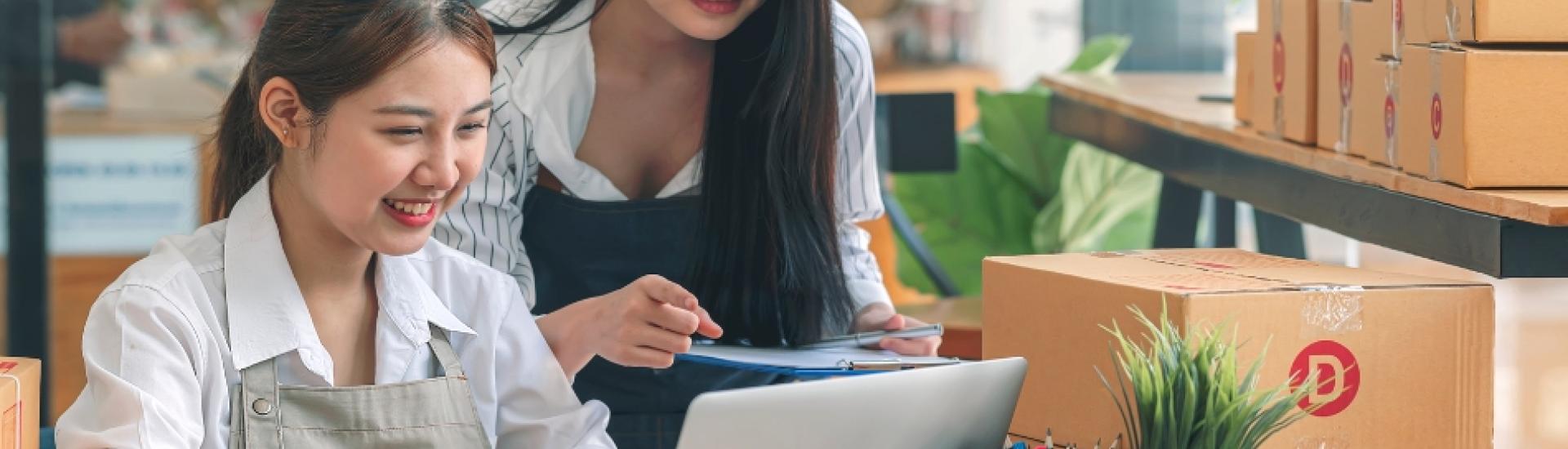 Two ladies looking at a laptop in a boxing/plant business