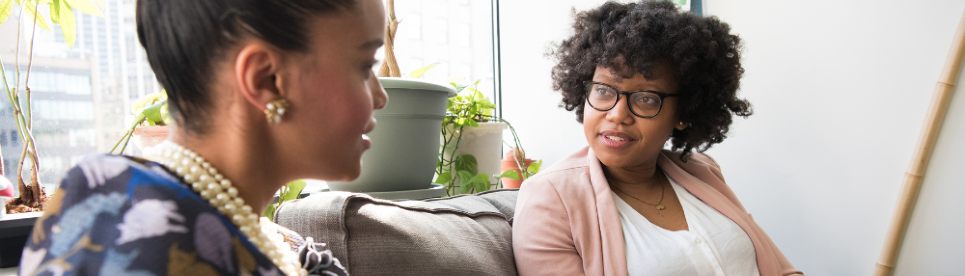 two women sat on sofa talking to each other