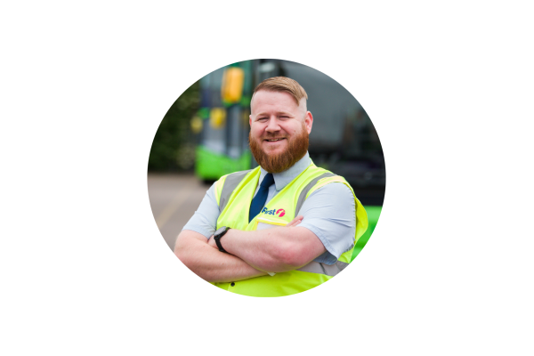 Photo of man with ginger hair standing in front of bus wearing a yellow high viz jacket. David