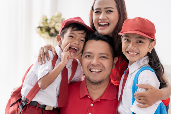 Parents hugging their two children who are dressed in school uniform
