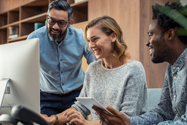 three people smiling looking at a computer screen