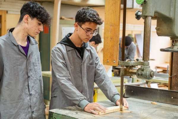 Two apprentices using a wood cutter