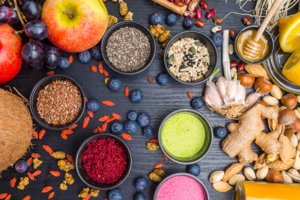 A flatlay of nutritional food: coconuts, applies, berries, nuts, lemons, yoghurts, seeds