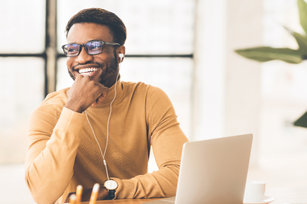 Man with glasses smiling at his work desk